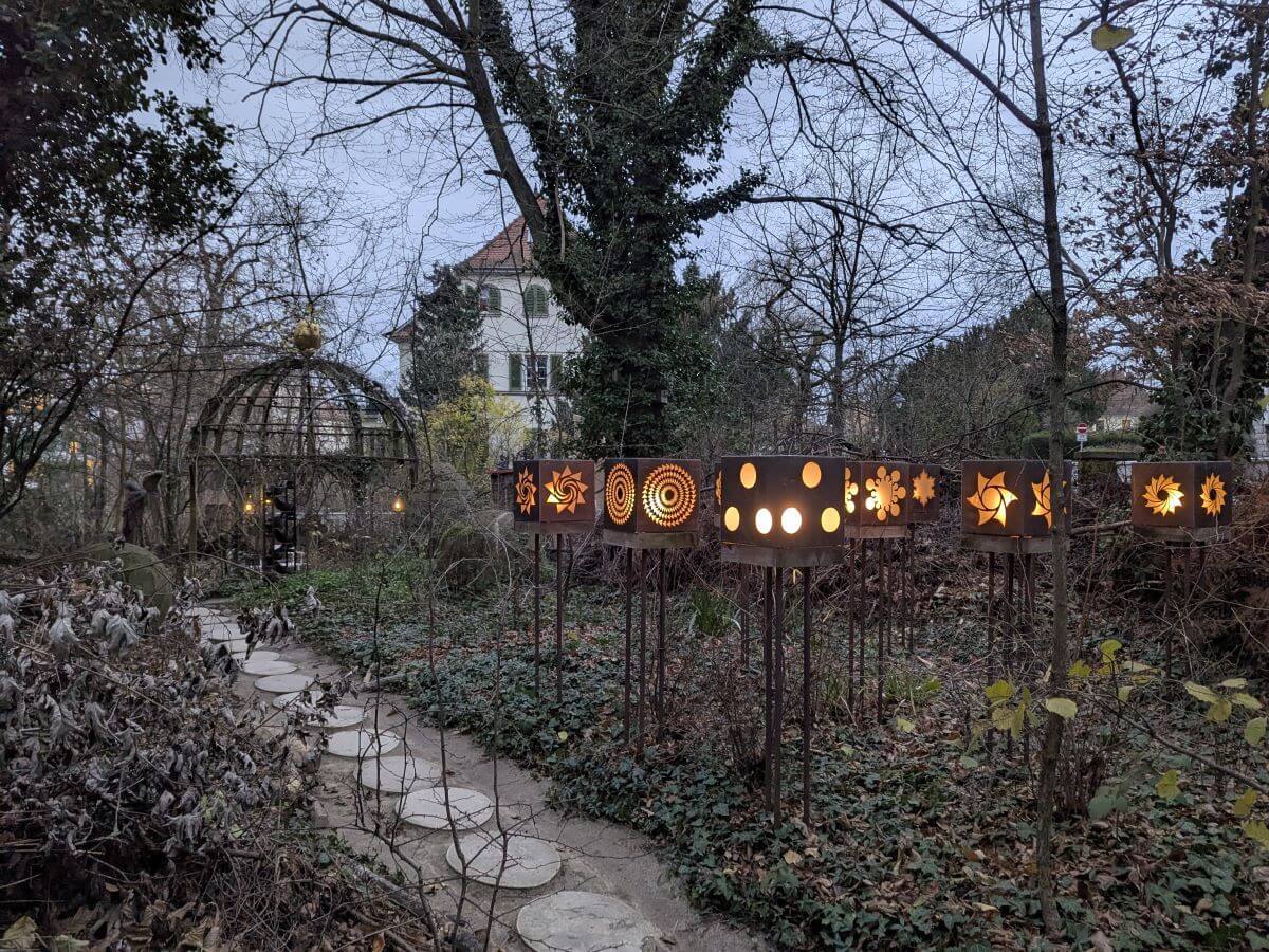 Stimmungsvolle Szene im Vortex Garten mit dekorativen Laternen und einem einladenden Pavillon, eingebettet in die harmonische Natur.